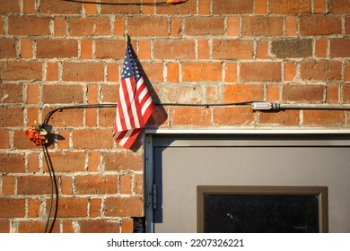 Small American Flag Hanging On Old Brick Wall