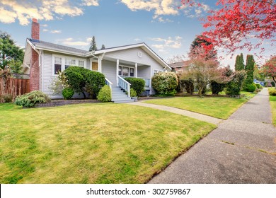 Small American Home With Light Exterior And A Large Grass Filled Lawn.