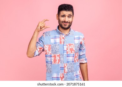 Too Small Amount! Portrait Of Disappointed Man In Blue Casual Style Shirt Showing A Little Bit Gesture, Dissatisfied With Low Rating, Measuring Scale. Indoor Studio Shot Isolated On Pink Background.