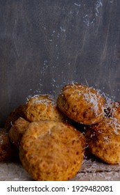 A Small Aperture Photograph Depicting A Pile Of Cheese Scones Being Dusted With Grated Parmesan Cheese Against A Grey Background. 