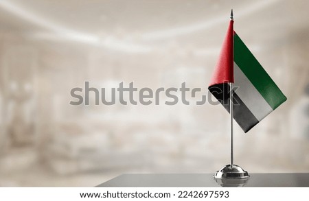A small Arab Emirates flag on an abstract blurry background.