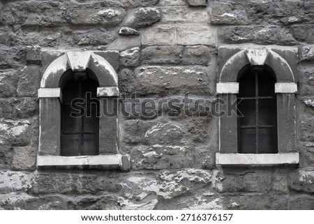 Small arched windows in grey stone church wall for use as a background texture