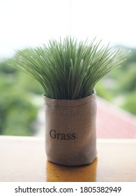 A Small Artificial Grass In The Sand Bag On The Table In The Balcony Garden