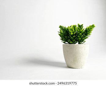 A small artificial plant with vibrant green leaves sits in a textured white pot against a clean white background. - Powered by Shutterstock