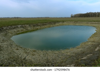 Small artificial shallow reservoir. A beautifully colored pond. Spring landscape.
