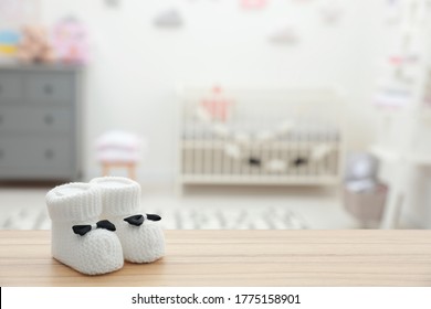 Small Baby Booties On Wooden Table In Room. Space For Text
