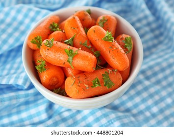 Small Baby Carrots In Soup Plate On Blue Napkin