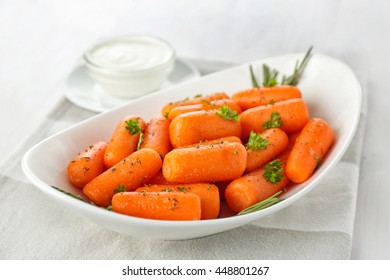 Small Baby Carrots In White Soup Plate On Table