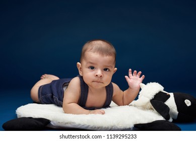 Small Baby With Hand Up Saying Hi In Blue Studio Background