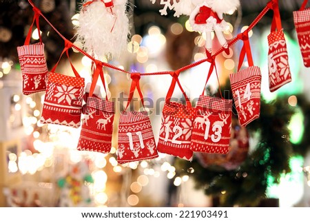 Small bags as Advent calendar with Sweets surprises hanging on a ribbon against lights blurred background