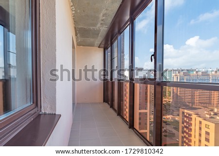 Small balcony interior in modern apartment building beige tiled floors and black window frames