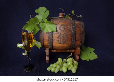 Small barrel of wine with grapes and a glass of wine.