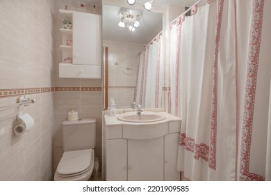 Small Bathroom With White Wood Vanity With Rectangular Mirror, Pink Patterned Shower Curtains, And Tile Trim