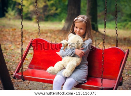 Small beautiful girl embraces an amusing bear
