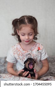 A Small Beautiful Rottweiler Puppy Amusing Opens A Flock. Pink Uvula Of A Puppy. Cute Little Girl With A Beautiful Smile And A Small Rottweiler Puppy.