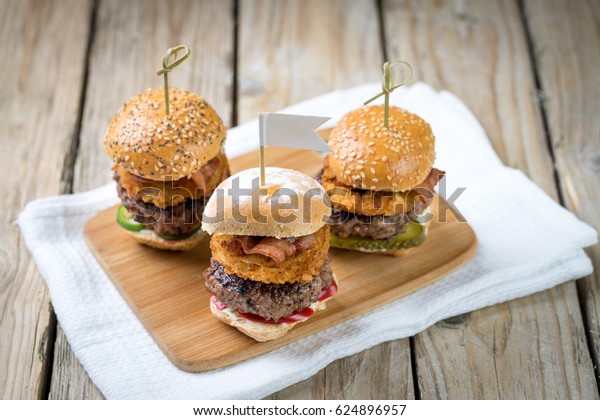 Small beef sliders grilled\
burgers onion rings little buns bacon served as appetisers for\
sharing  