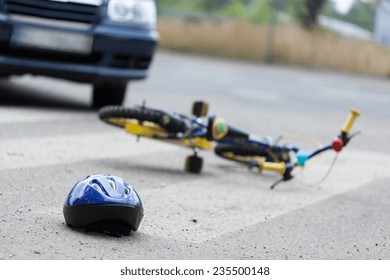 A small bike and a helmet lying on the road
