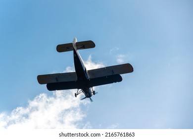 Small Biplane Flying Against The Blue Sky