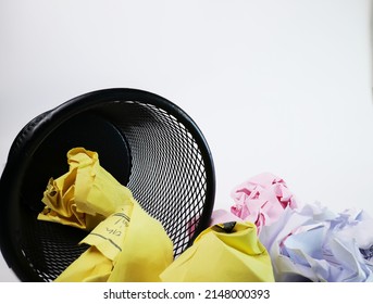 A small black basket made of round iron fell down. It is used to put the trash, documents that are not working and are overflowing to the outside. In the white background there is a copy space.