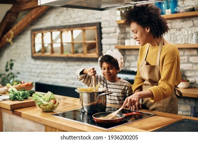 Small black boy preparing food with his mother in the kitchen.  - Powered by Shutterstock