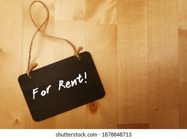 Small Black Chalkboard On Wooden Copy Space Background With Text Handwritten FOR RENT, Concept Of  Make Money Or Earn Extra Income From Rent Out Room Or Home Or Property