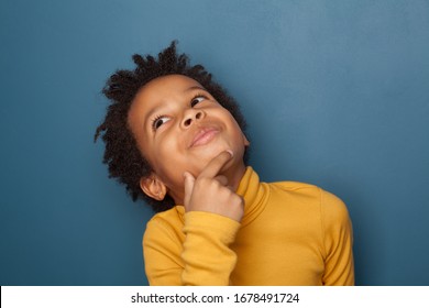 Small Black Child Boy Thinking And Looking Up On Blue Background