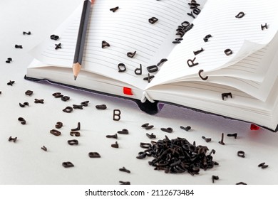 a lot of small black Latin letters scattered across the pages of a notebook and a table, the concept of grammar and spelling, creativity and ideas for a story - Shutterstock ID 2112673484