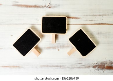 Small black posters in frames on a white wooden background. Template for inscriptions.