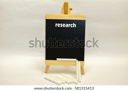 Small blackboard written "research" with pile of white chalks isolated over white background