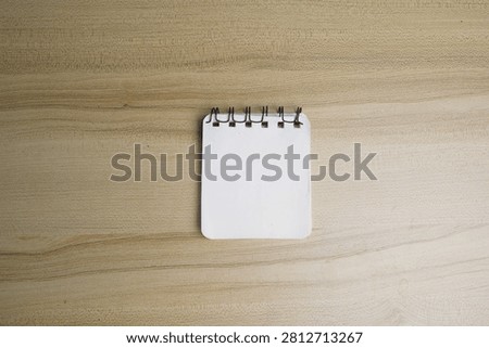 A small, blank spiral notebook placed on a wooden surface, ready for notes or sketches.