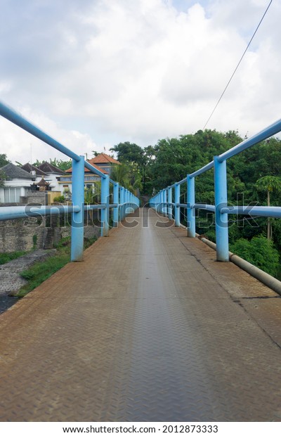 A small blue bridge made of iron. A small\
bridge connecting two\
villages.
