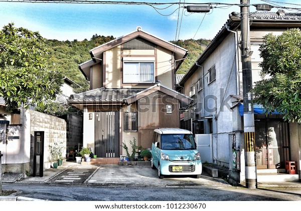 The\
small blue car in front of the tiny house that is traditional\
Japanese house in Kyoto, Japan on 22 November\
2016