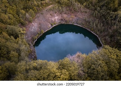 Small Blue Crater Lake Of A Dormant Volcano Surrounded By Forest In Autumn Colors In Germany