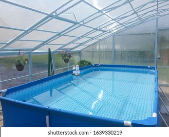 small blue frame pool filled with clear water stands in a transparent polycarbonate pavilion, lifestile, countryside vacation, summer