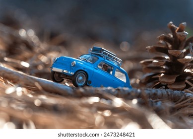 Small blue toy car journeys amidst pine cones and golden autumn leaves - Powered by Shutterstock