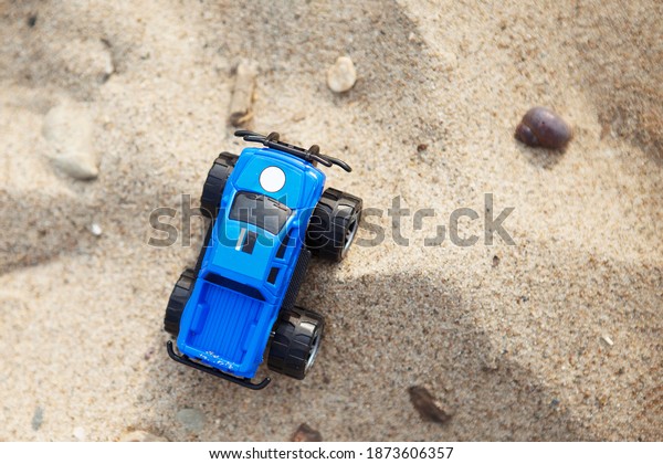 Small\
blue toy car is standing on the sand. Top\
view.