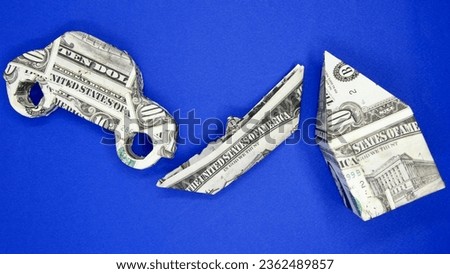 Small boat, house and car model made with dollar bills on blue background. Origami paper shapes
