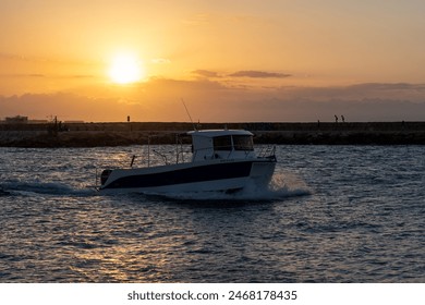 Small boat or motorboat sailing in the port with people in the background on the reef. - Powered by Shutterstock