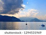 small boat on Lake Maggiore with mountains and cloudy blue sky in background in Pallanza Verbania, North Italy