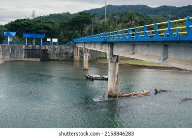 Small Boat Under A Tall Bridge