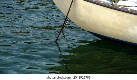 Small boats moored in a harbour floating in clear water with ripples and textures in bright sunlight