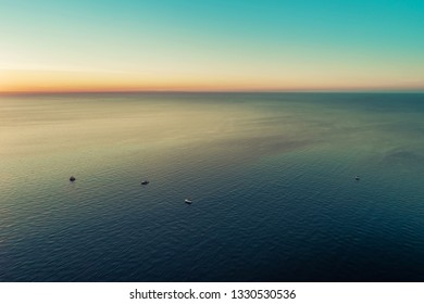 Small boats in vast sea at dusk - aerial view with copy space