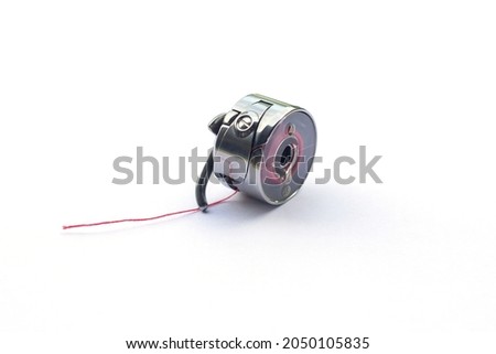 Small bobbin or shuttle is tools or parts of an electric sewing machine isolated on white background.
