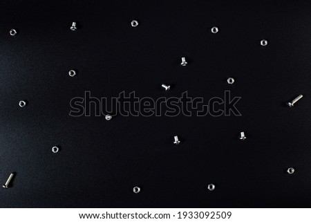 Small bolts and nuts making flatlay on black background.
