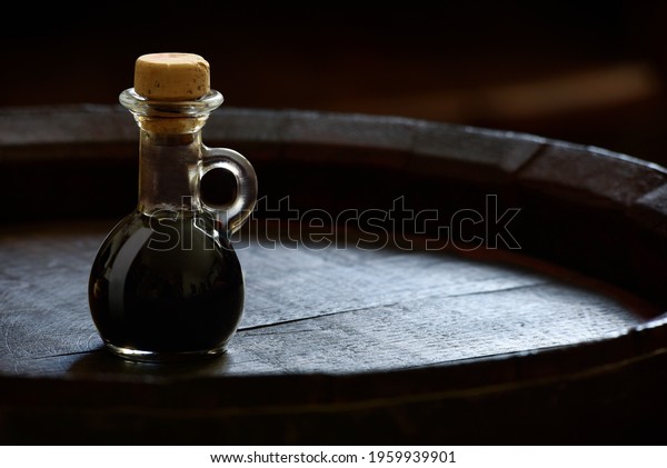 Small bottle of balsamic vinegar of Modena on a wooden\
barrel 