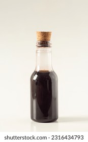 Small bottle with coffee liqueur, or dark liquid inside, decorative on a white background, isolated perfect for artwork, selective focus