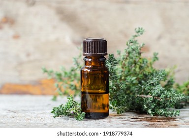 Small Bottle With Essential Thyme Oil (extract, Tincture, Infusion, Perfume). Aromatherapy, Spa And Herbal Medicine Ingredients. Old Wooden Background. Copy Space 