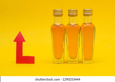 Small Bottles Of Alcohol On A Yellow Background And A Red Arrow Concept Of Raising The Price Of Alcohol, Close-up, Markup