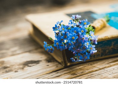 Small bouquet of blue forget-me-not flowers with old book on the wooden background. Selective focus. Shallow depth of field. - Powered by Shutterstock