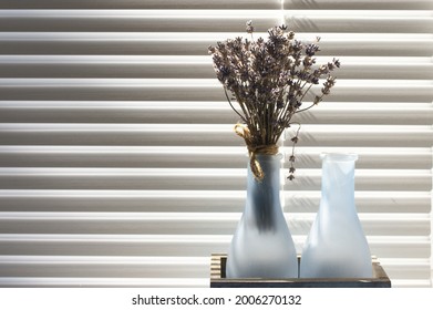 Small bouquet of dry lavender in rustic vase on sill agaist shutters at sunny day. - Powered by Shutterstock